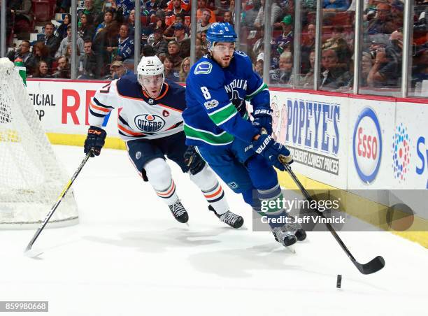 Christopher Tanev of the Vancouver Canucks and Connor McDavid of the Edmonton Oilers skate after a loose puck during their NHL game at Rogers Arena...