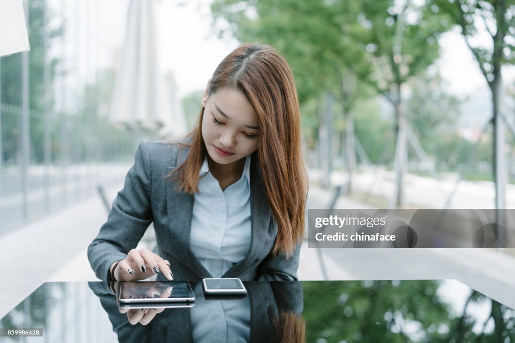 Woman using tablet PC while sitting at sidewalk cafe