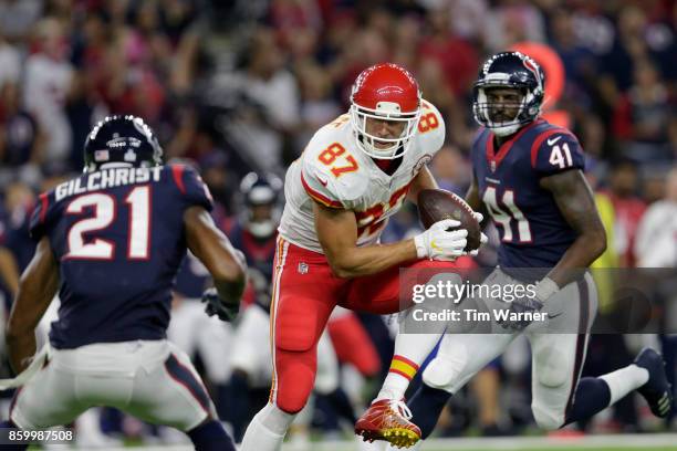 Travis Kelce of the Kansas City Chiefs runs between Zach Cunningham of the Houston Texans and Marcus Gilchrist after a first half catch at NRG...