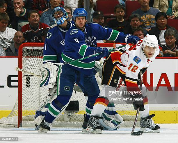 Kevin Bieksa of the Vancouver Canucks checks Jarome Iginla of the Calgary Flames as Roberto Luongo of the Vancouver Canucks looks on during the game...