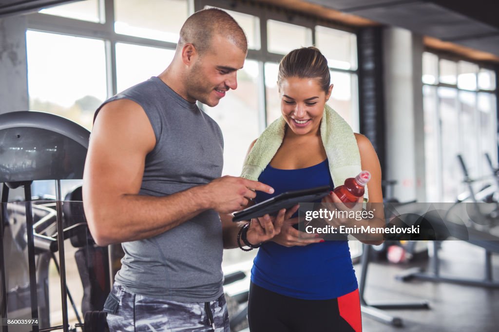 Giovane donna che discute dei progressi dell'allenamento con l'istruttore di fitness