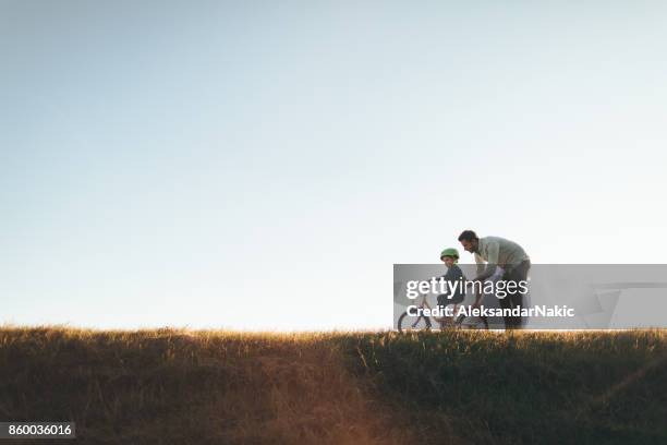 vater und sohn auf einem fahrradweg - child and parent and bike stock-fotos und bilder