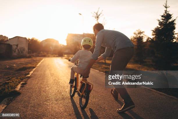 father and son on a bicycle lane - showing stock pictures, royalty-free photos & images