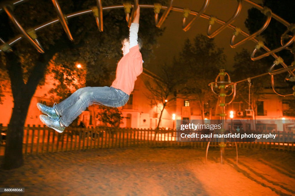 Boy playing on playground equipment after dark