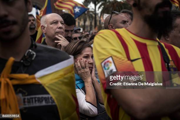 Pro- independence supporters react as they hear Catalan President Carles Puigdemont announce he will abide by the independence vote as they watch on...