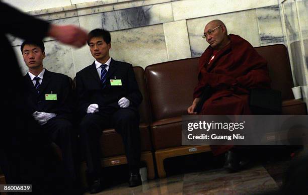 Chinese soldiers dressed as ushers sit next to a Buddhist monk delegate from Tibet areas during the third plenary session of the annual National...