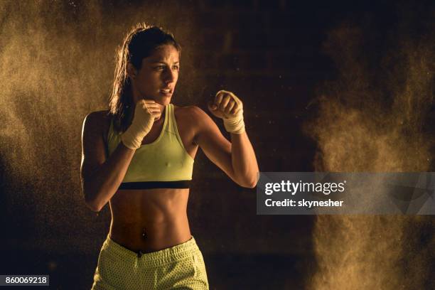 gespierd bouwen atleet in een gevechten houding op een bokstraining. - boxing   womens stockfoto's en -beelden