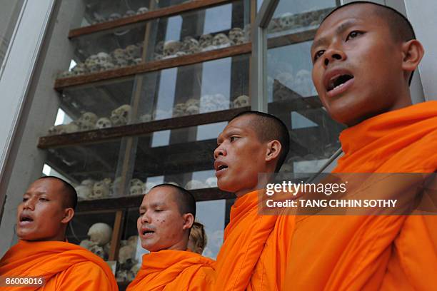 Cambodian Buddhist monks pray in front of skulls displayed at the Choeung Ek center built on the 'killing fields' in Phnom Penh on April 17, 2009....