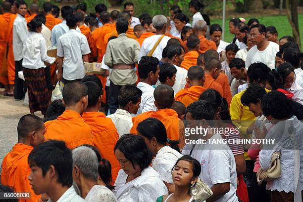 Cambodian people offer food an alms to Buddhist monks at the Choeung Ek center built on the 'killing fields' in Phnom Penh on April 17, 2009....