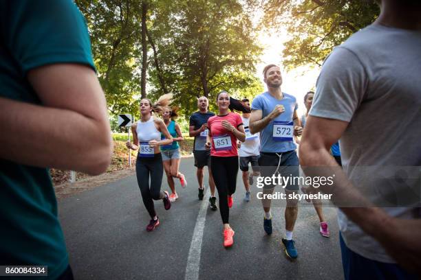 grupo de gente atlética feliz corriendo una carrera de maratón por la naturaleza. - carrera de carretera fotografías e imágenes de stock