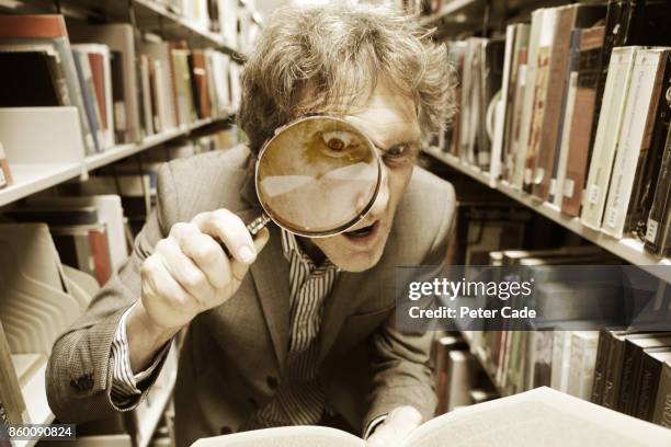 crazy man looking in book with magnifying glass - petits caractères photos et images de collection