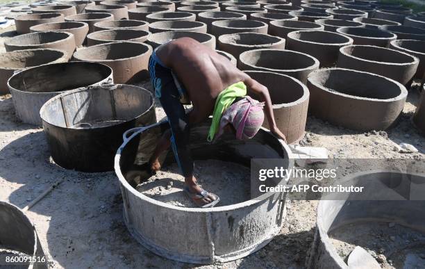 Bangladeshi boy paints the inside of a metal mould to make a toilet chamber rings at Sonarpara in Cox's Bazar on October 11, 2017. With the sudden...