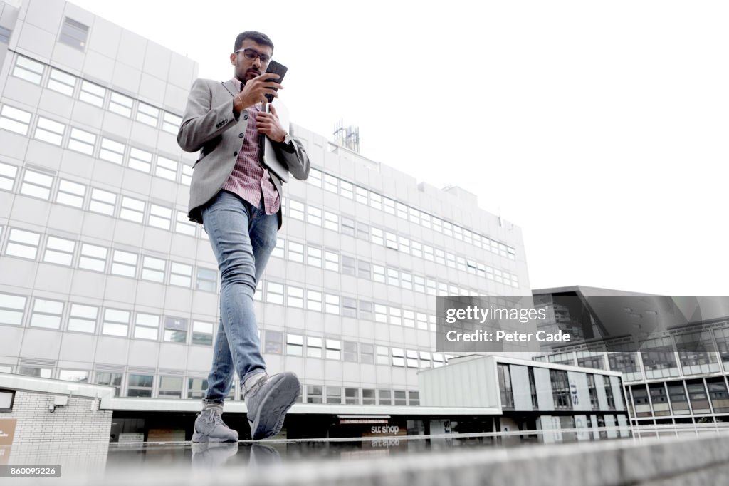 Man walking in city looking at mobile phone