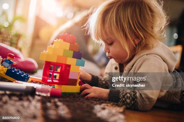 small boy playing with plastic blocks on the floor. - toy building blocks stock pictures, royalty-free photos & images
