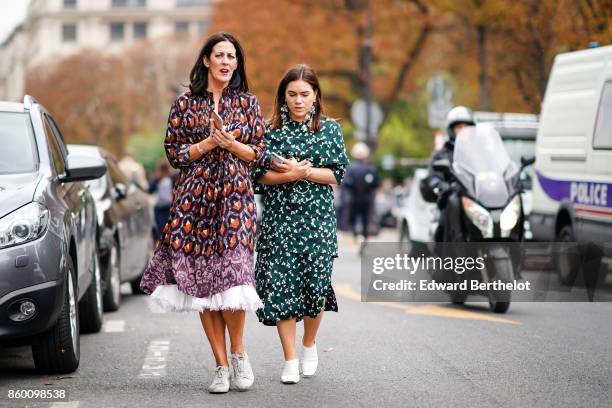 Guest wears a purple and brown print dress over a white petticoat, white sneakers ; a guest wears a green spotted gathered dress, white shoes,...