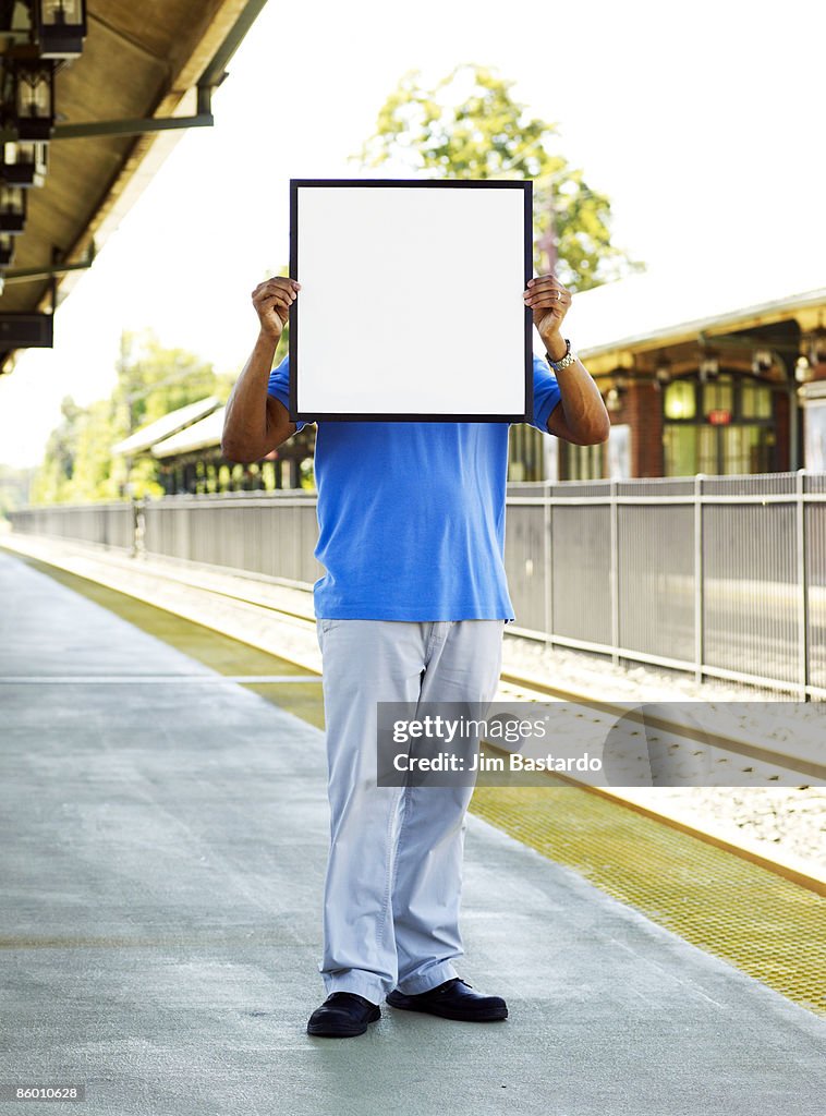 Man with sign over face in town