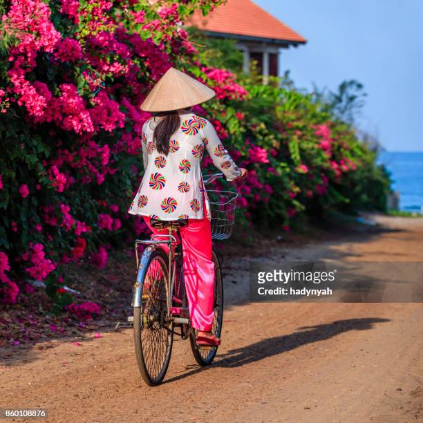 vietnamese vrouw fietsen, vietnam - asian style conical hat stockfoto's en -beelden