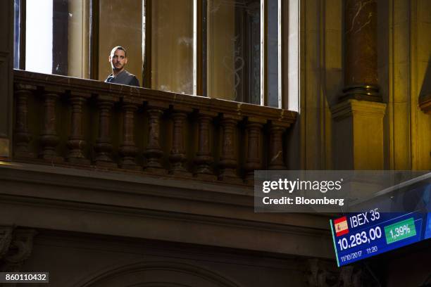 Visitor looks on from a balcony above an electronic screen displaying IBEX 35 stock price news in the main hall of the Madrid Stock Exchange, also...