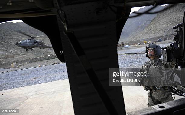 Crew member of US Army UH-60 Black Hawk helicopter watches an AH-64 Apache helicopter taking off at ISAF's Camp Wright in Asadabad, in Afghanistan's...