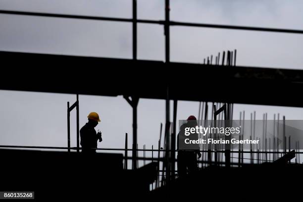 The silhouettes of two construction workers ic pictured on October 11, 2017 in Berlin, Germany.