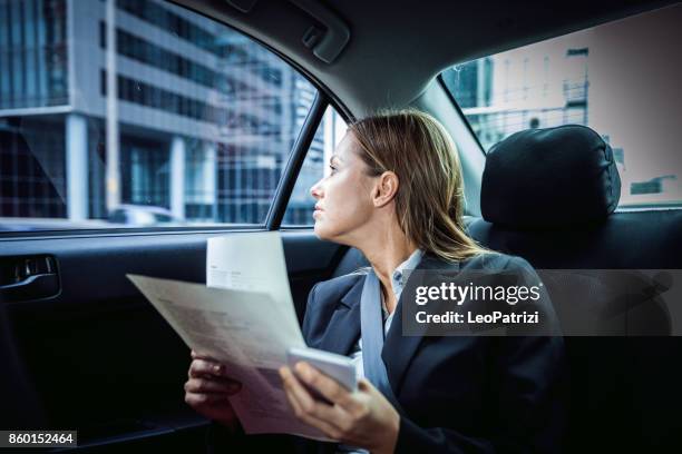 on the go - businesswoman heading to a meeting in downtown - australia taxi stock pictures, royalty-free photos & images