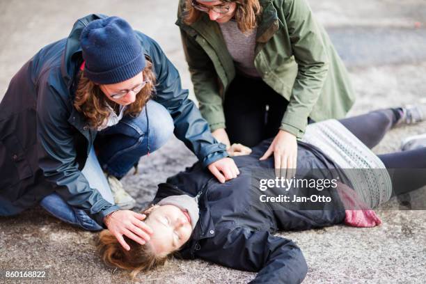 dos mujeres buscando mujer inconsciente - cpr fotografías e imágenes de stock