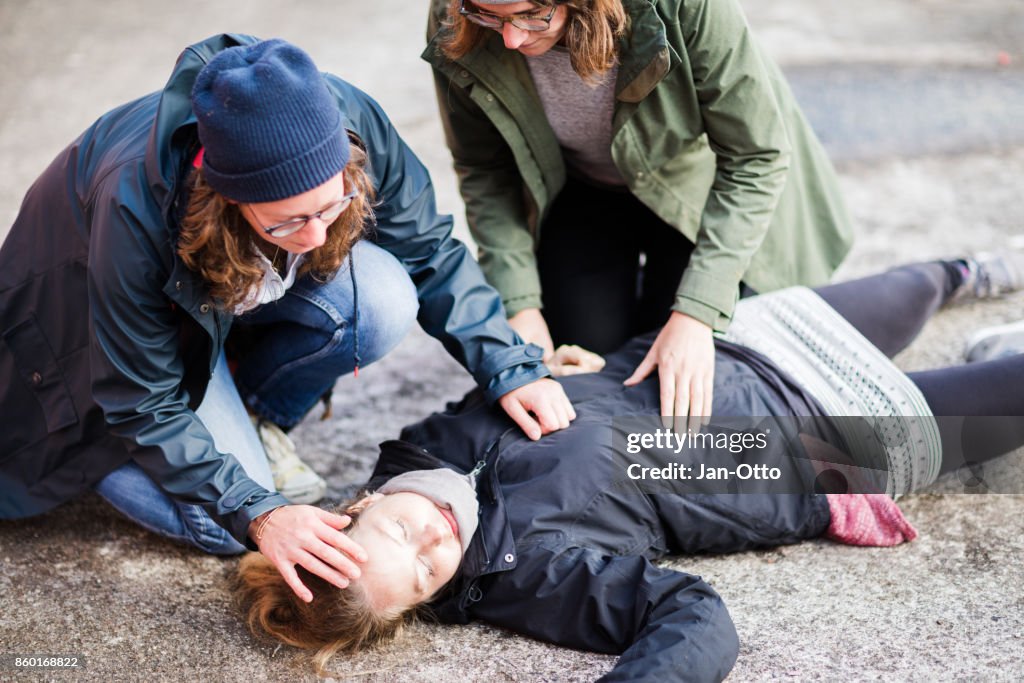 Two woman looking after unconscious woman