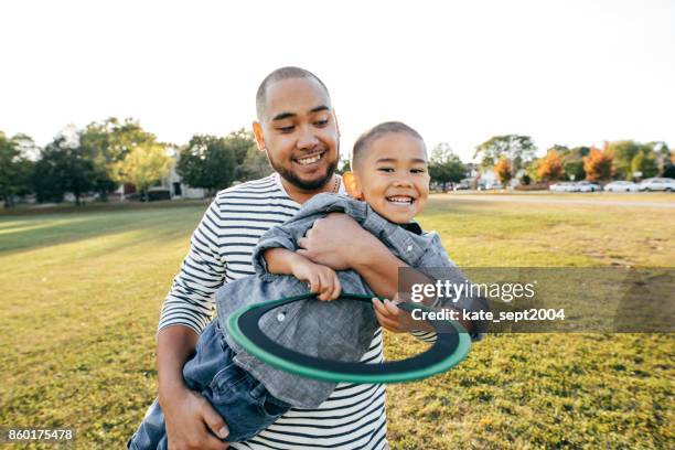 spielen mit einem vater im freien - asian family in park stock-fotos und bilder