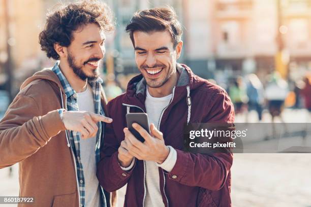 two young men having fun - man on cell phone walking in the city stock pictures, royalty-free photos & images