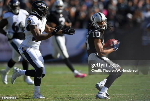 Seth Roberts of the Oakland Raiders looks to avoid the tackle of Brandon Carr of the Baltimore Ravens during the third quarter of their NFL football...