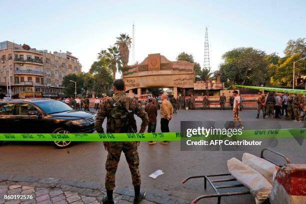 Graphic content / Syrian security forces stand guard outside the main entrance to the police headquarters in Syria's capital Damascus on October 11...