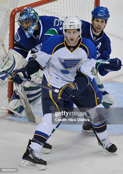 David Backes of the St. Louis Blues waits for a shot while being checked by Willie Mitchell of the Vancouver Canucks as Roberto Luongo of the...