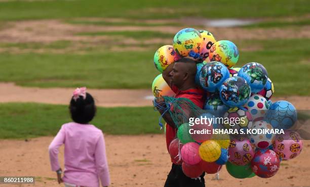 Sri Lankan vendor sell toy balls on the Galle Face promenade in the center of the Sri Lankan capital of Colombo on October 11, 2017. / AFP PHOTO /...