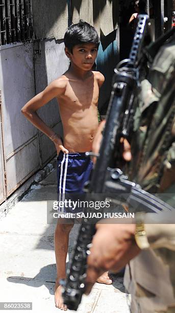 An Indian child watches paramilitary soldiers patrol a lane adjacent to the special bomb-proof court at Arthur Road jail in Mumbai on April 18, 2009....