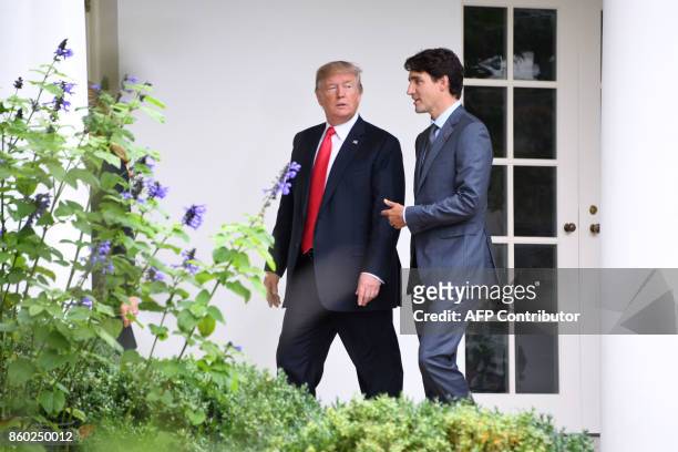 President Donald Trump listens to Canadian Prime Minister Justin Trudeau as they walk towards the Oval Office of the White House in Washington, DC,...