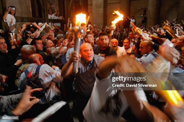 Orthodox Christian Palestinians rush thorugh the crowd as they race to bring burning candles to their churches across the Holy Land during the Holy...