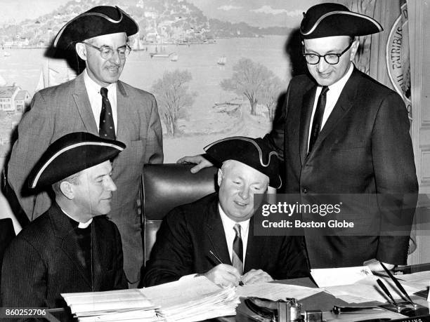 Boston Mayor John F. Collins signs a document of incorporation for the Freedom Trail Foundation at Boston City Hall circa December 1964. Seated at...