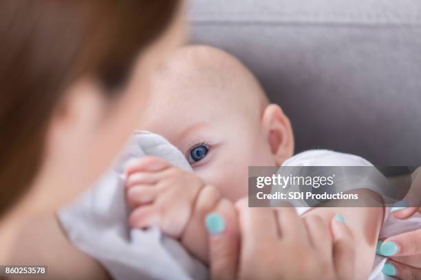 adorable bebé de ojo azul mira mamá durante la lactancia - blue eyes fotografías e imágenes de stock