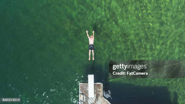 overhead shot of young male diving into lake water - lake auburn stock pictures, royalty-free photos & images