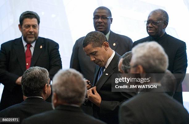 President Barack Obama puts away his pen after signing an autograph, next to St Vincent & the Grenadines' Prime Minister Ralph Gonsalves, St Kitts &...