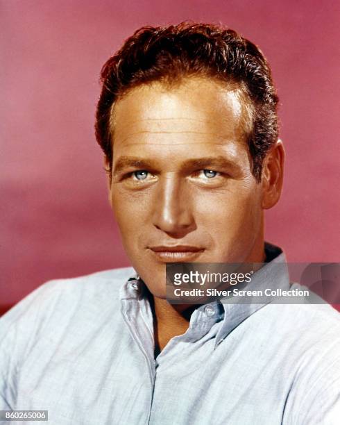 Portrait of American actor Paul Newman as he poses against a pale red background, 1960s.