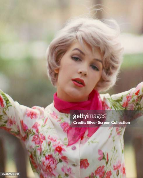Portrait of American actress Stella Stevens, in a flower print top and pink scarf, late 1960s.