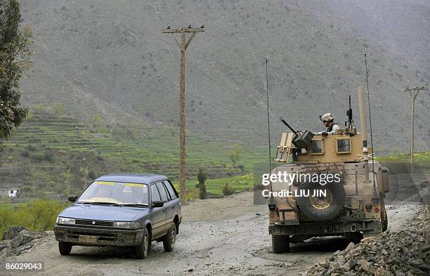 Afghanistan-unrest-military-Security" by Charlotte McDonald-Gibson A civilian car drives past a US army humvee guarding a road during a patrol near...