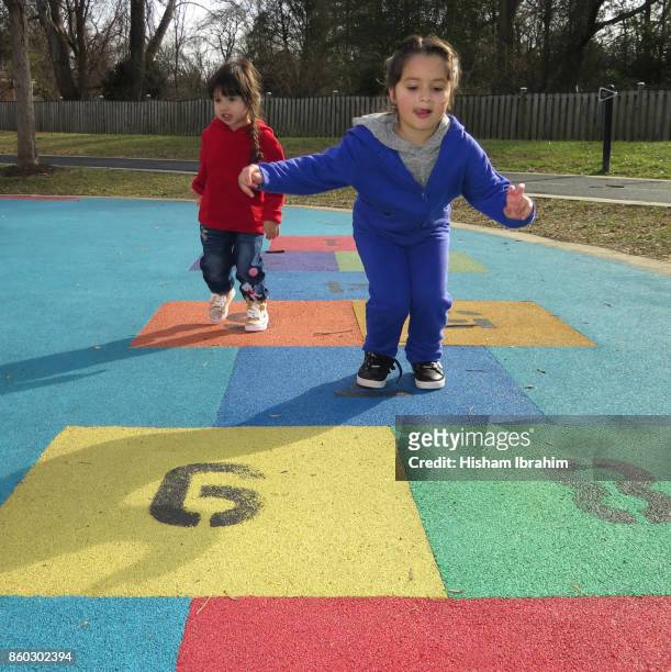two beautiful sisters 3 years and 5 years playing hopscotch game at playground. - 4 5 years stock-fotos und bilder