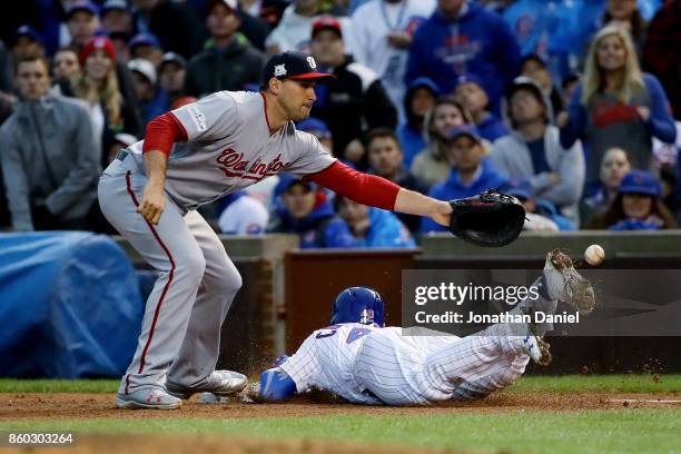 Willson Contreras of the Chicago Cubs dives into first base for a single past Ryan Zimmerman of the Washington Nationals in the fourth inning during...