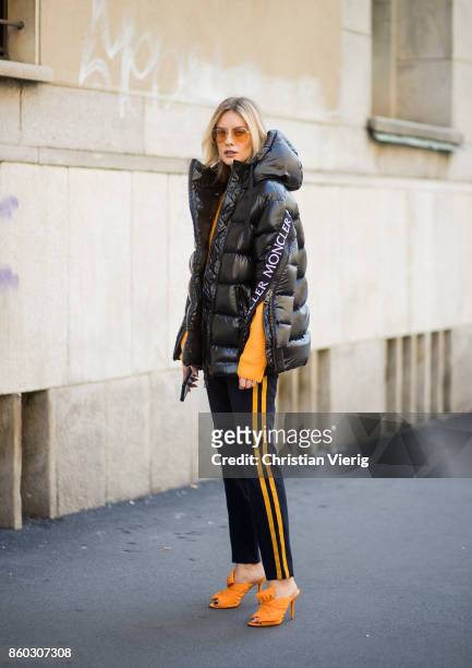 Lisa Hahnbueck wearing a black puffer jacket Moncler x Stylebop, orange 81hours knit, black Set pants with stripes, orange Charlotte Olympia Bow...