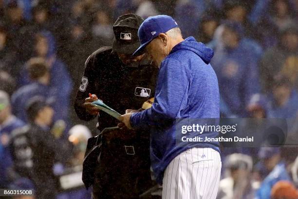 Manager Joe Maddon of the Chicago Cubs discusses a substitution with umpire Laz Diaz in the eighth inning during game four of the National League...