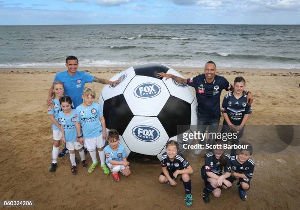 Melbourne City player Tim Cahill and Melbourne Victory's Archie Thompson pose with with kids from Melbourne City and Melbourne Victory junior...