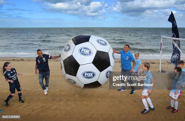 Melbourne City player Tim Cahill and Melbourne Victory's Archie Thompson play a game of beach soccer with kids from Melbourne City and Melbourne...