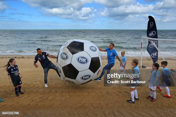 Melbourne City player Tim Cahill and Melbourne Victory's Archie Thompson play a game of beach soccer with kids from Melbourne City and Melbourne...